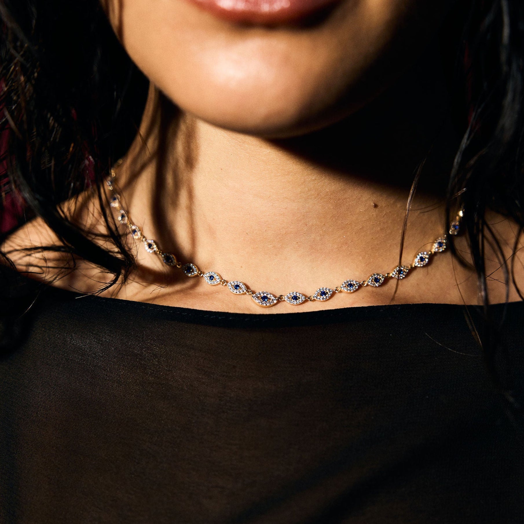 Close-up of a person wearing a blue evil eye tennis necklace