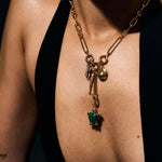 Gold necklace with a green gemstone pendant on a dark background