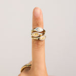 Gold ring with circular design on a finger against a plain background