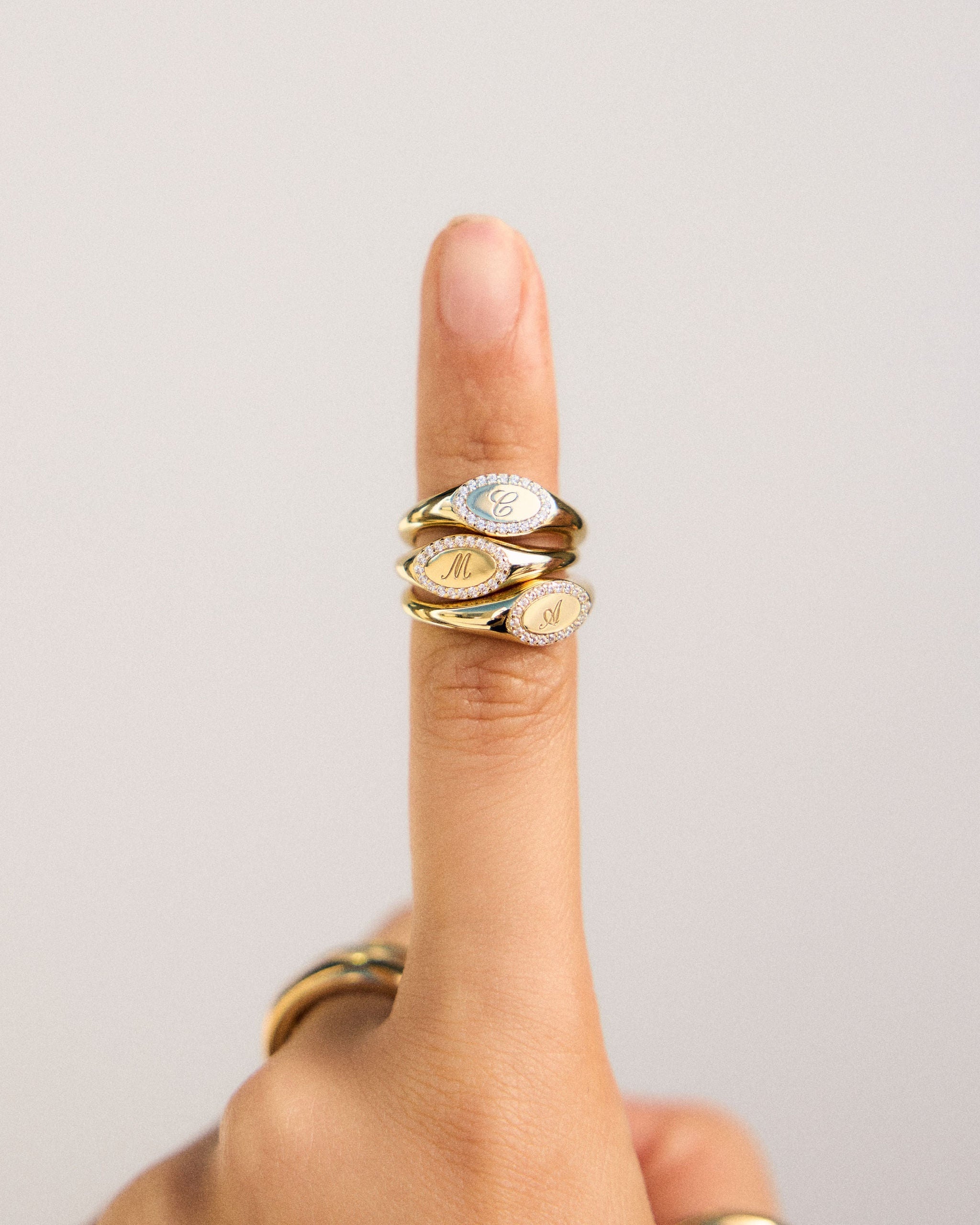 Gold ring with circular design on a finger against a plain background