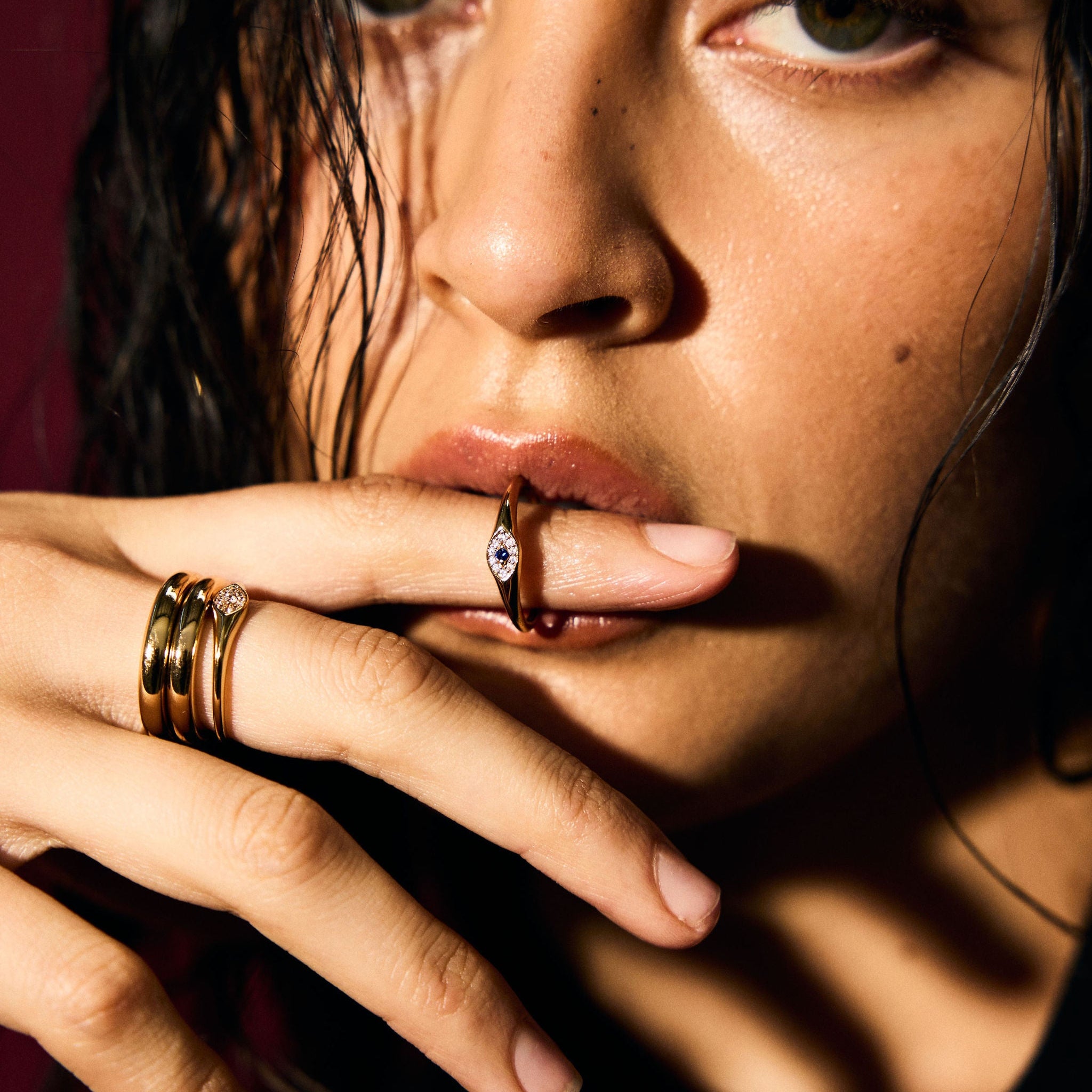 Close-up of a person with multiple rings on their fingers against a dark background