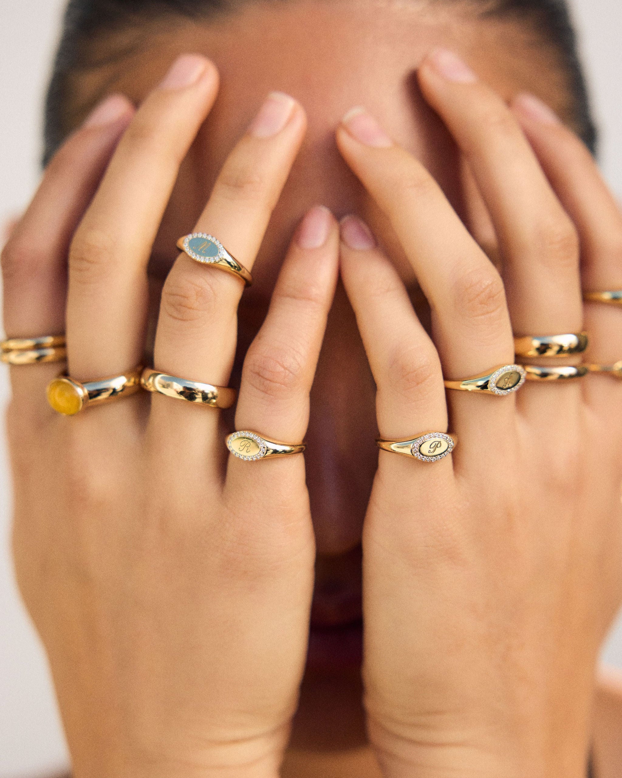 Close-up of hands wearing multiple gold rings with gemstones.