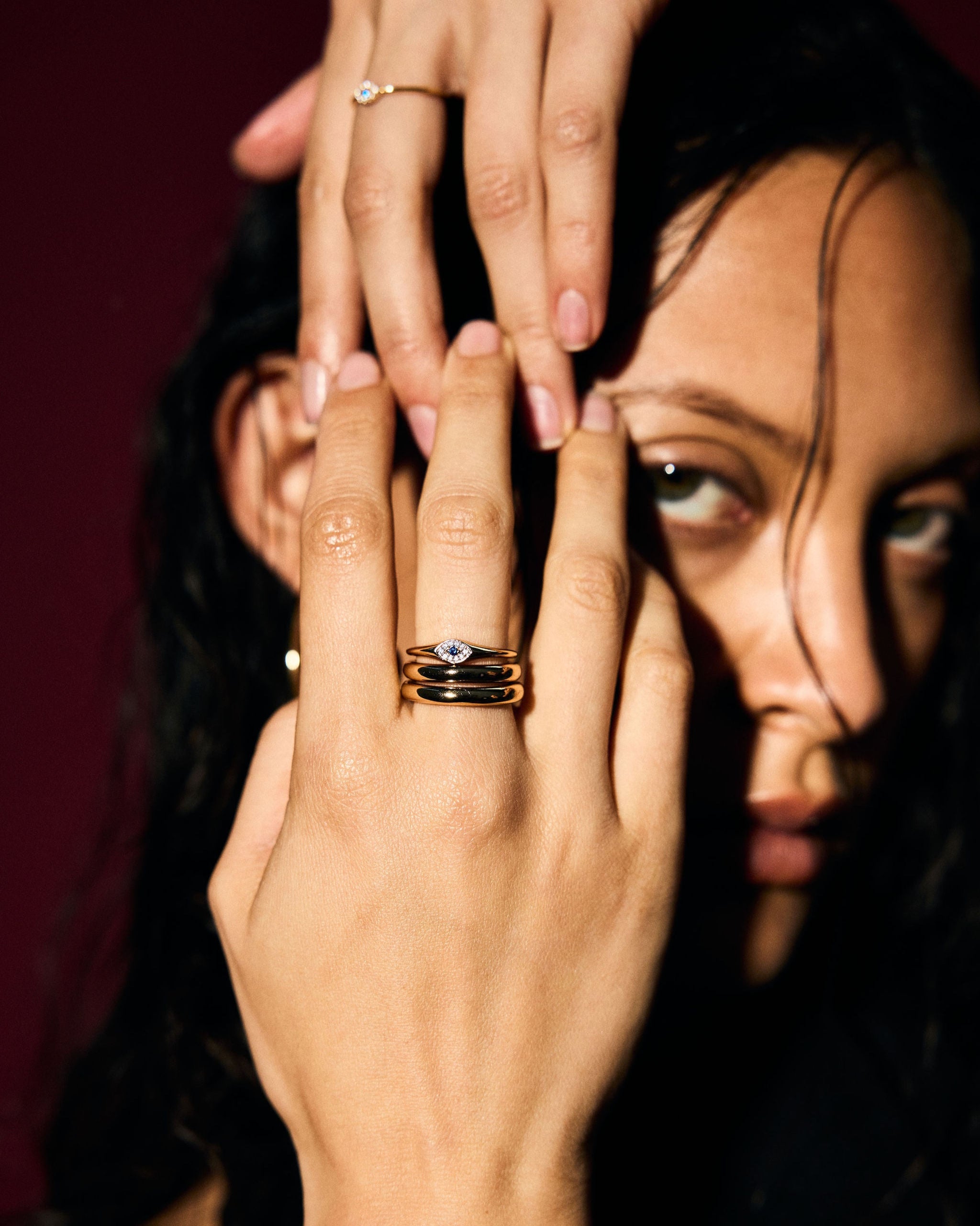 Close-up of a person's hand with an evil eye signet ring, focusing on the jewellery.