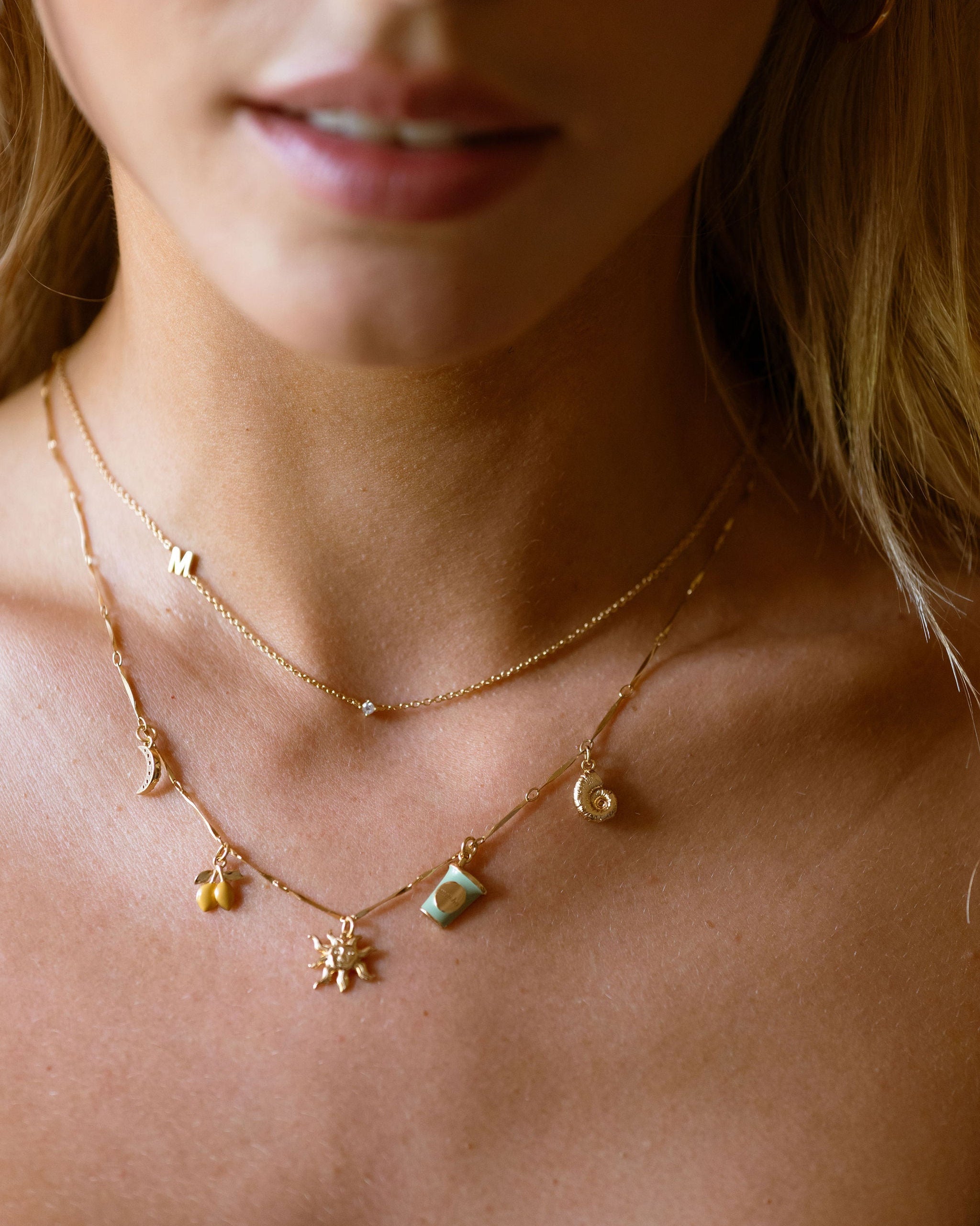 Close-up of a woman wearing a gold necklace with pendant