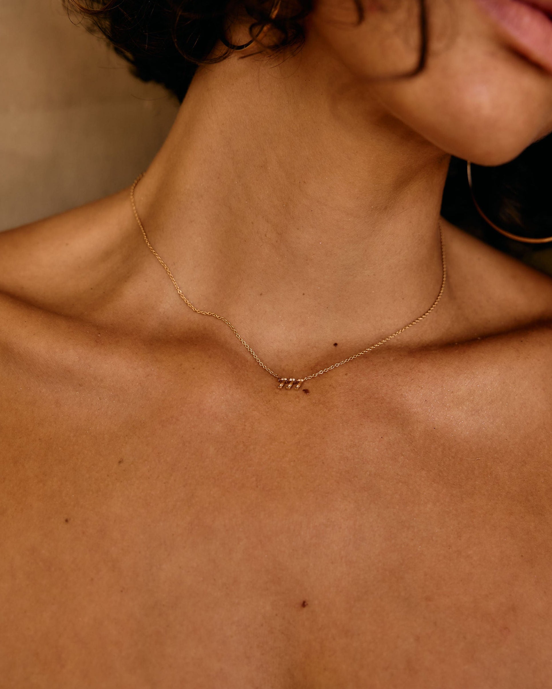 Close-up of a person wearing a delicate necklace with a neutral background
