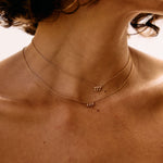 Close-up of a person wearing a delicate necklace with small pendants.