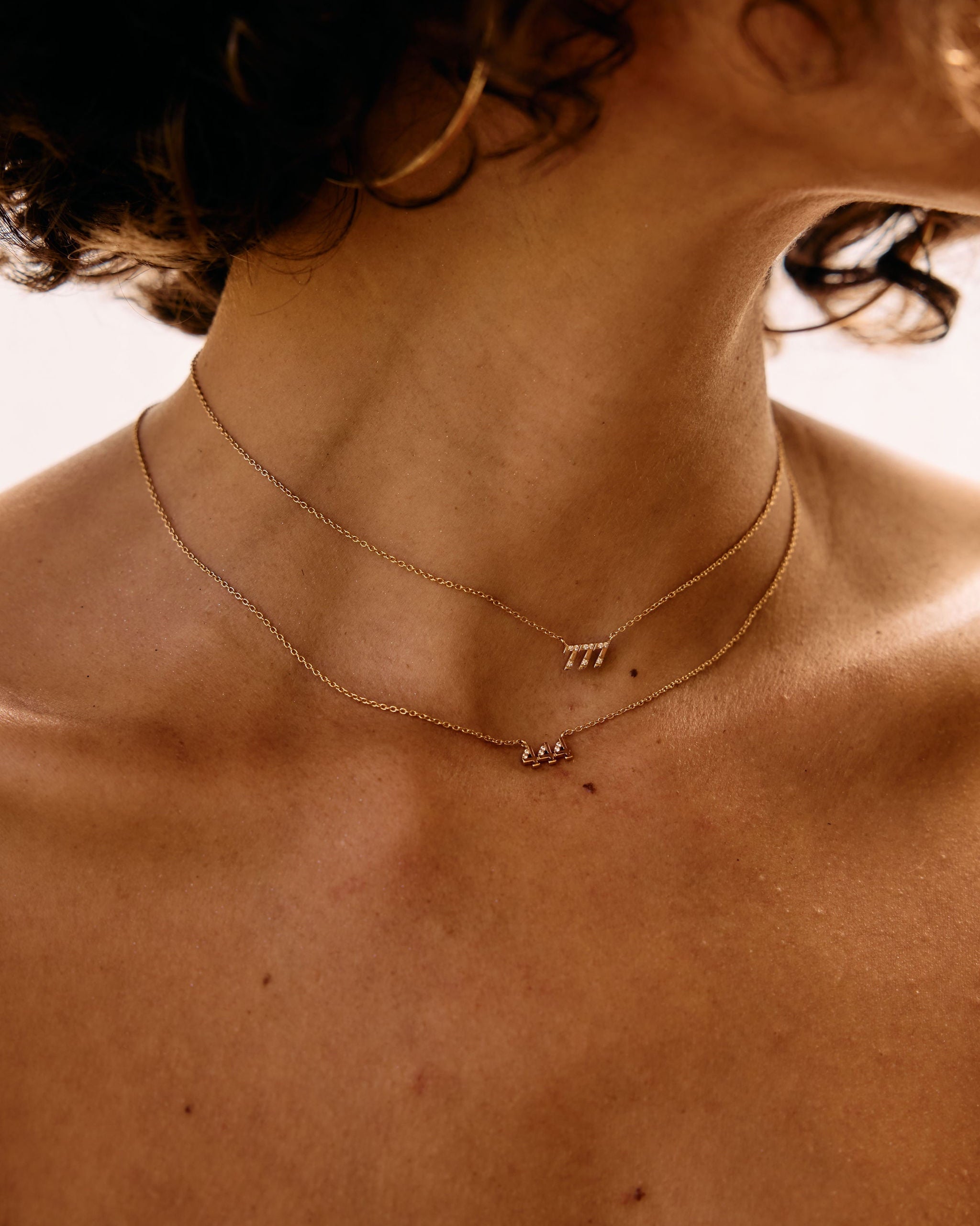 Close-up of a person wearing a delicate necklace with small pendants.