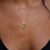 Gold necklace with a small pendant on a person wearing a black top.