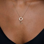 Gold necklace with a pendant on a person wearing a black top.
