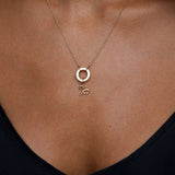 Gold necklace with a pendant on a person wearing a black top.