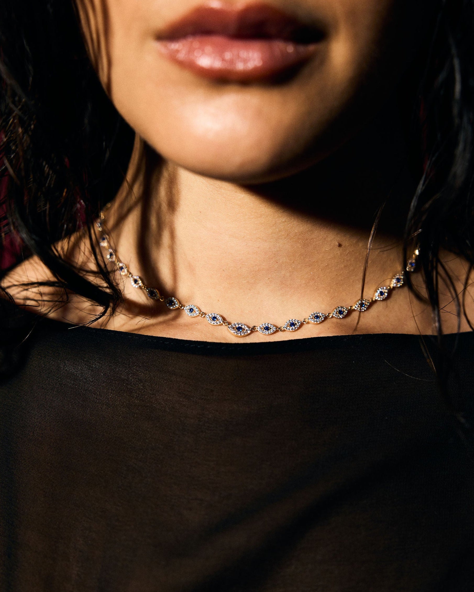 Close-up of a person wearing a blue evil eye tennis necklace