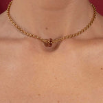 Gold necklace on a person's neck with a red background