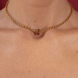 Gold necklace on a person's neck with a red background
