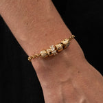 Gold bracelet with diamond beads on a wrist against a black background