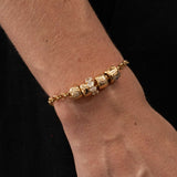 Gold bracelet with diamond beads on a wrist against a black background