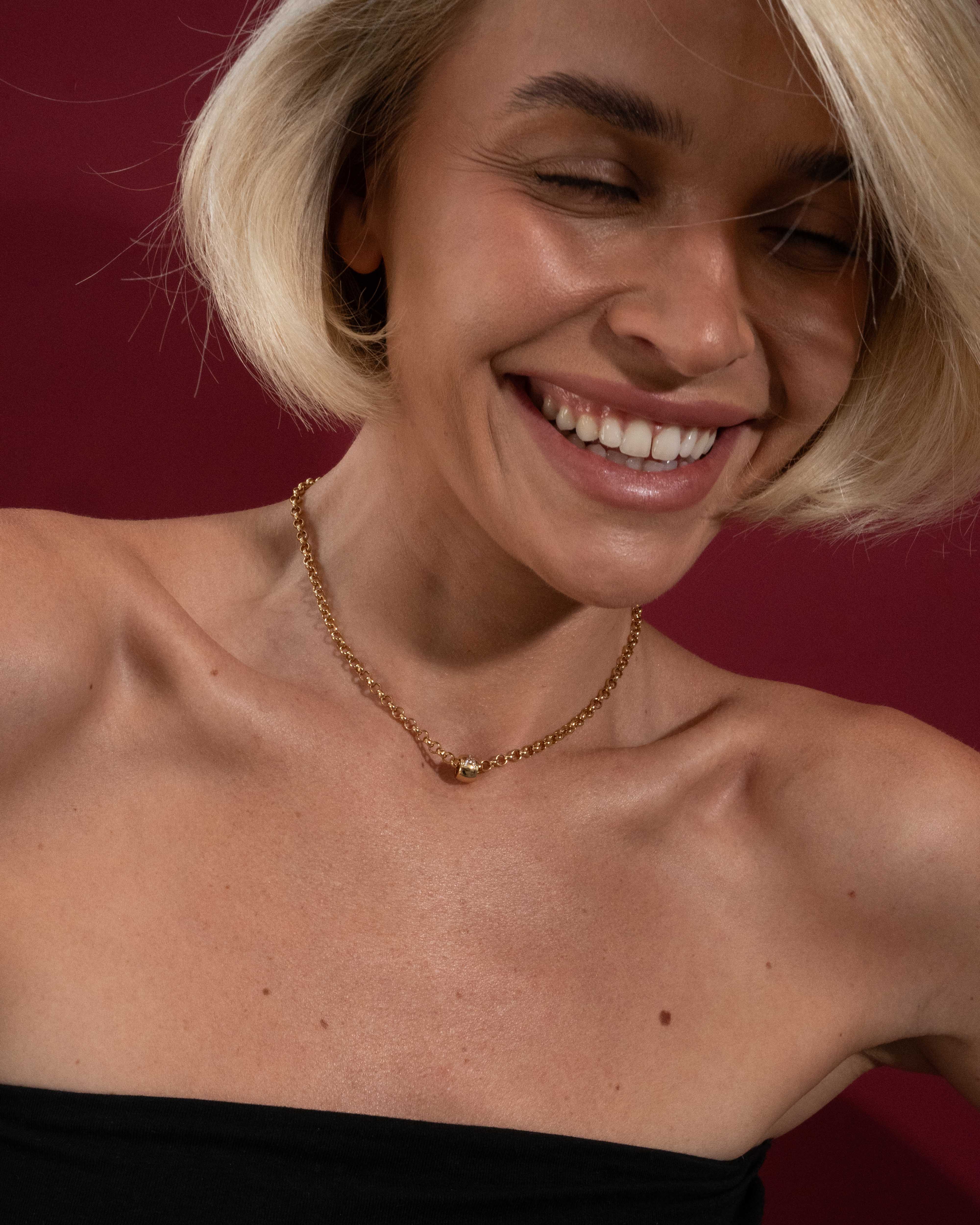 Woman wearing a gold necklace against a red background