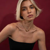 Woman with short blonde hair wearing a black top against a red background
