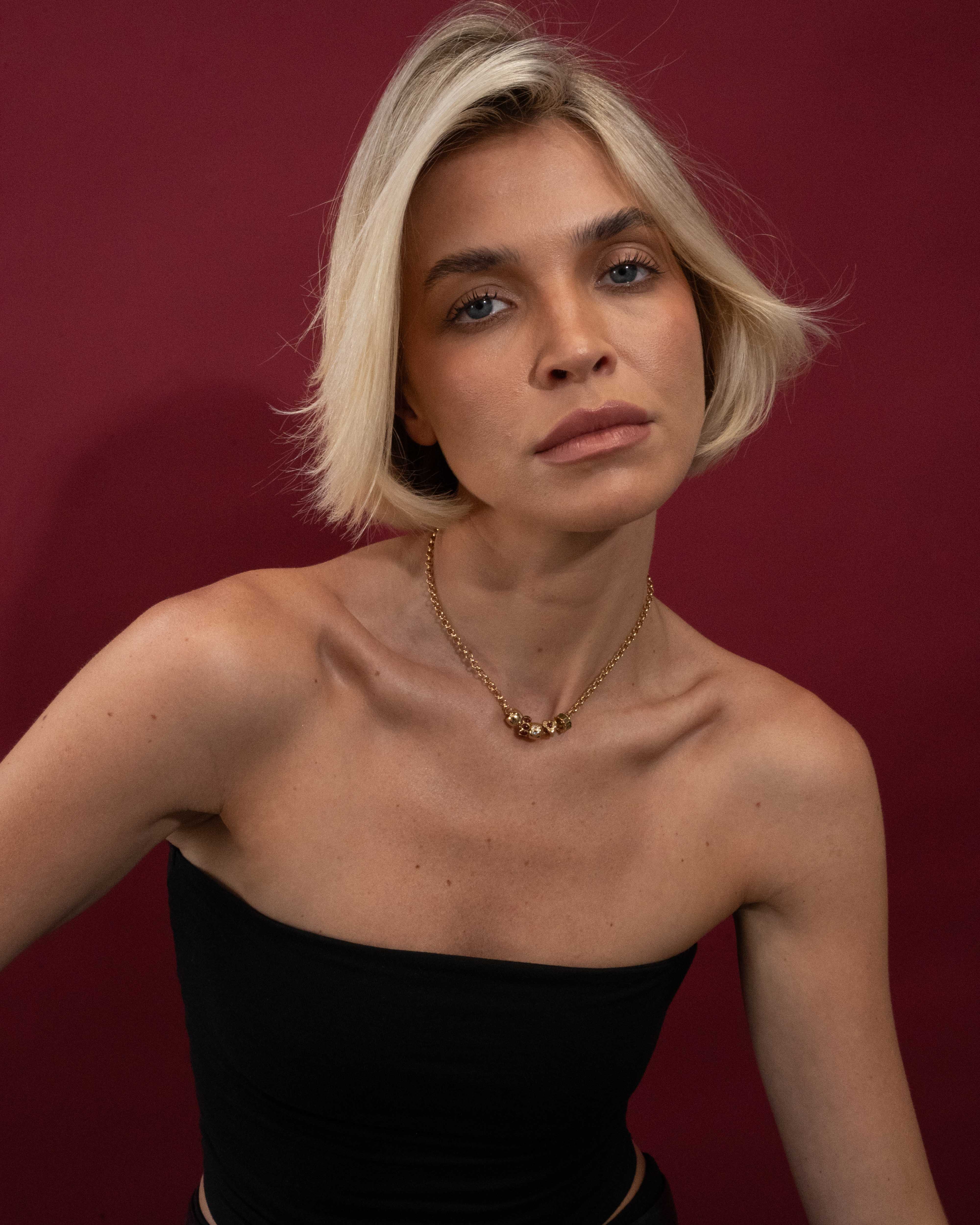 Woman with short blonde hair wearing a black top against a red background