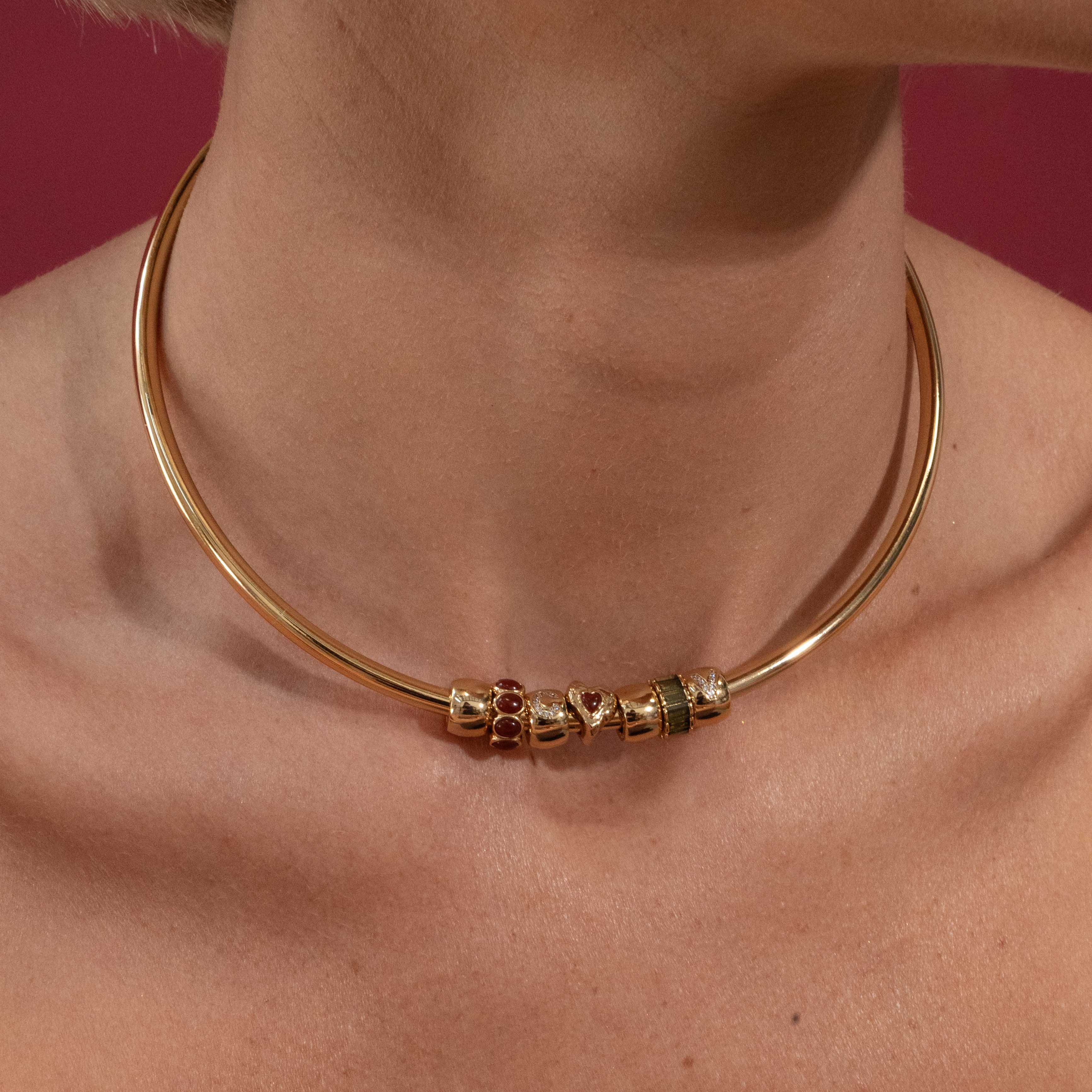 Gold necklace with beads on a person against a red background