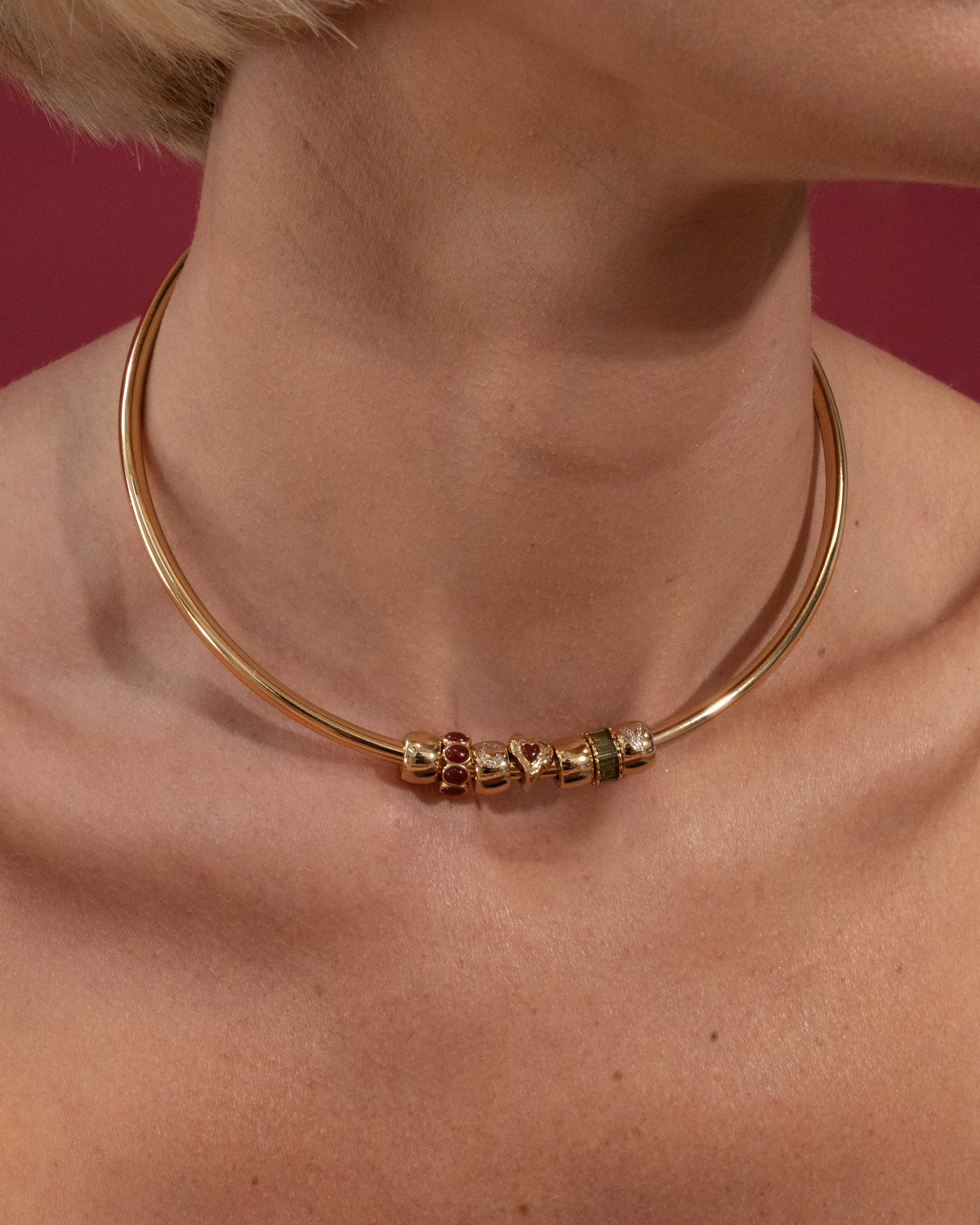 Gold necklace with beads on a person against a red background