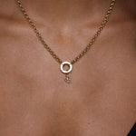 Gold necklace with a small pendant on a person wearing a black top.