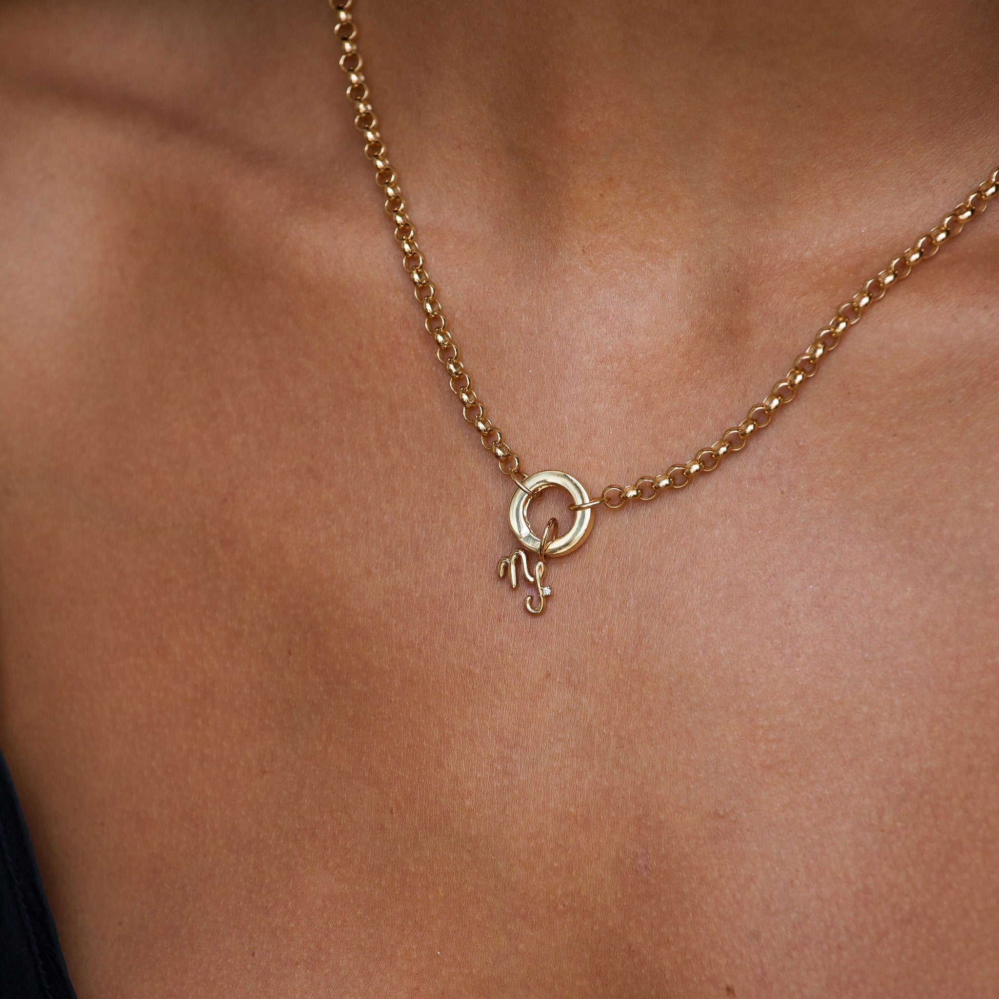 Gold necklace with a small round pendant on a person's neck