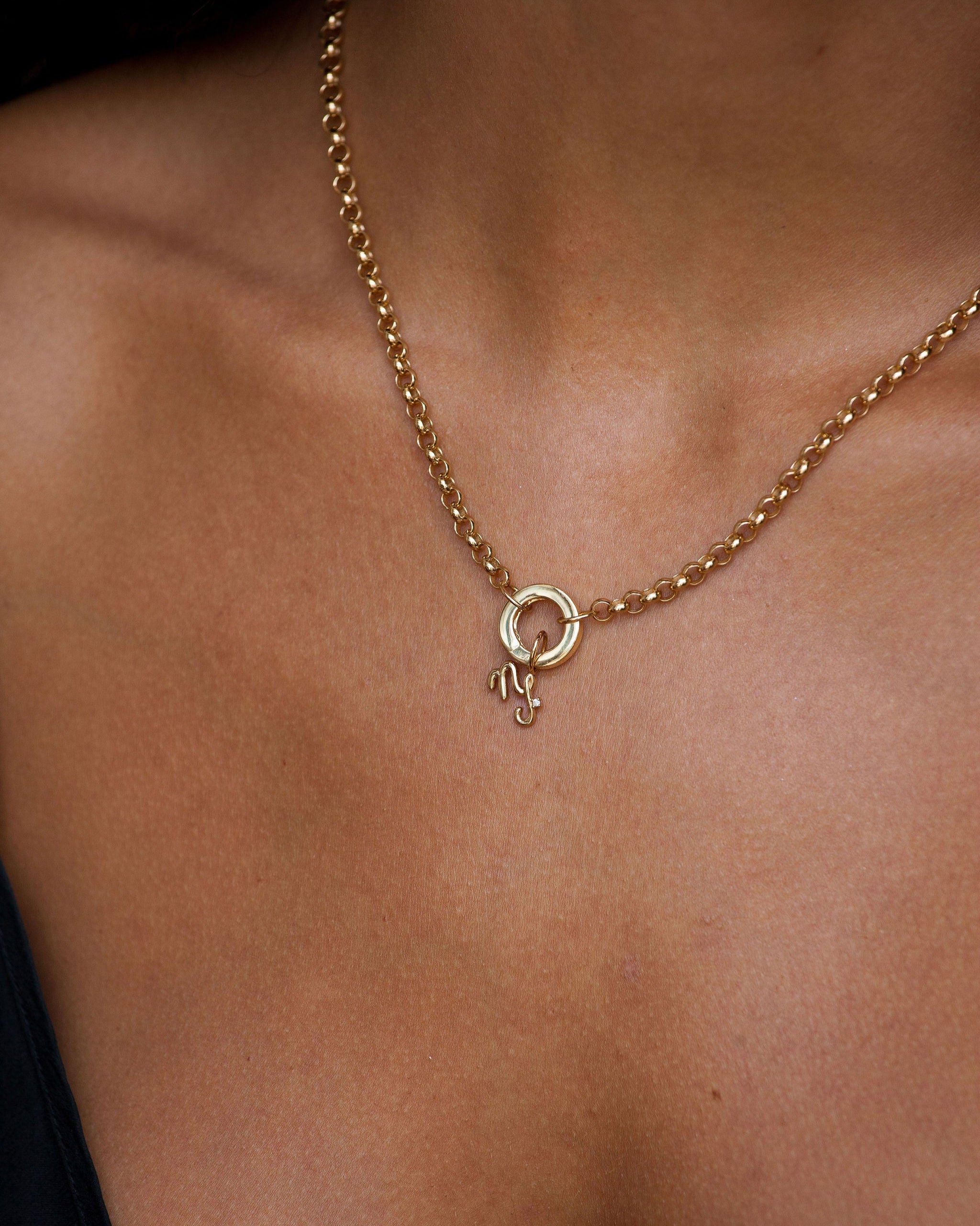 Gold necklace with a small round pendant on a person's neck