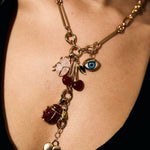 Gold necklace with various charms on a person wearing a black top.
