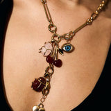 Gold necklace with various charms on a person wearing a black top.