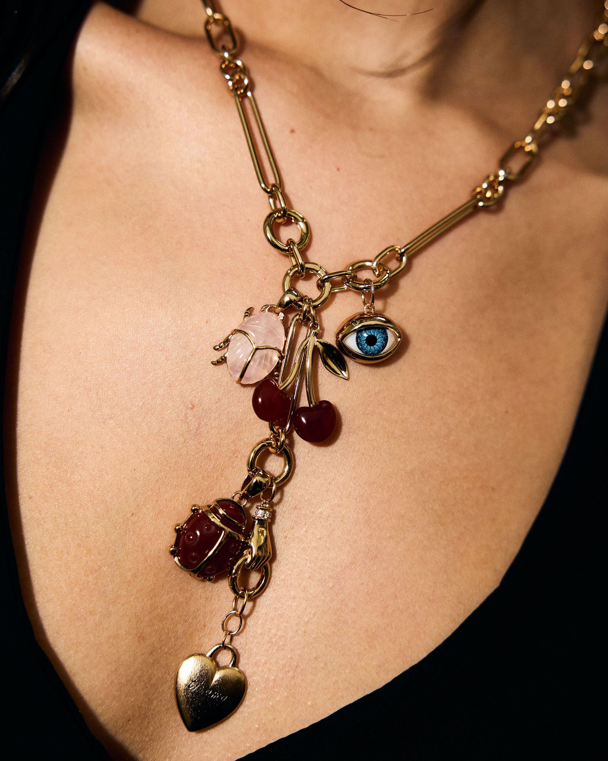 Gold necklace with various charms on a person wearing a black top.