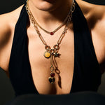 Woman wearing a necklace with multiple pendants against a dark background