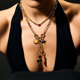 Woman wearing a necklace with multiple pendants against a dark background
