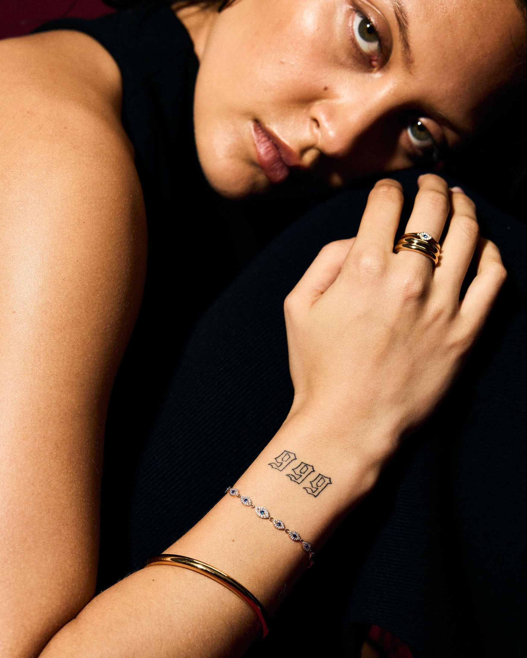 Close-up of a person with tattoos on their arm and hand, wearing stacked rings. 