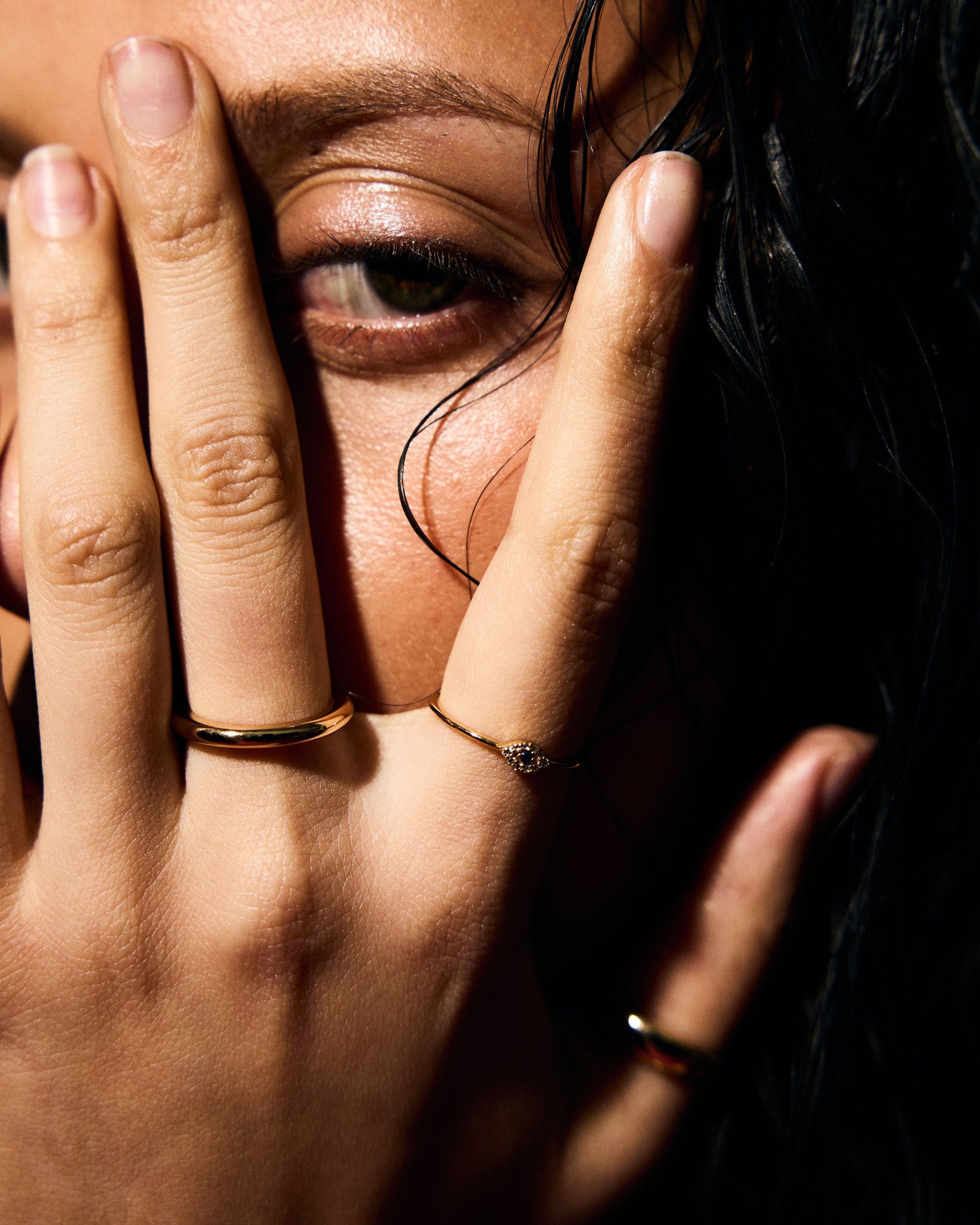 Close-up of a person covering their face with their hand with a fine ring
