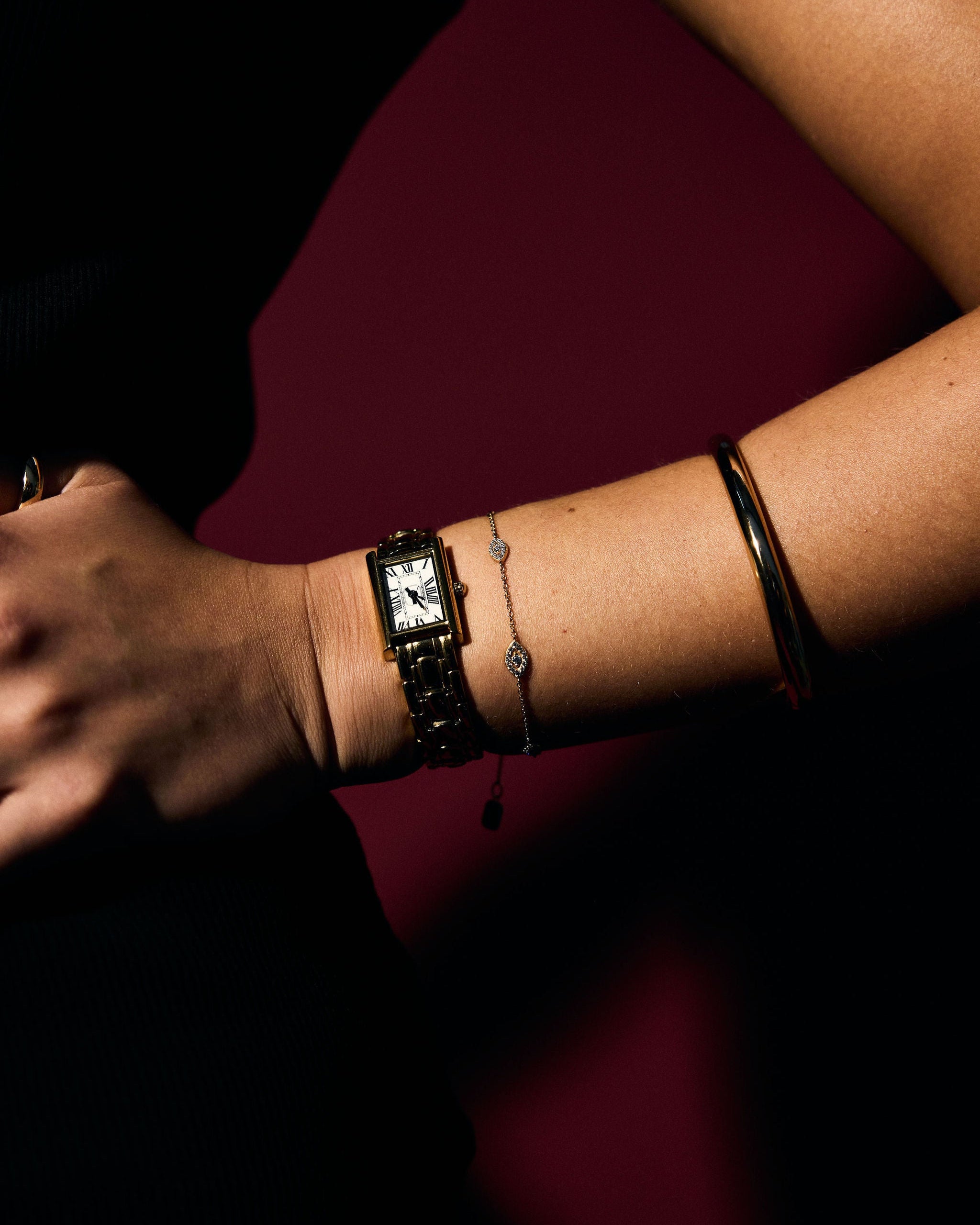 Close-up of a wrist wearing Fine Evil Eye Bracelets and a gold watch