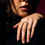 Close-up of a person with a hand resting on their face with a fine gold evil eye ring