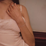 Woman in light pink dress wearing a tennis bracelet 