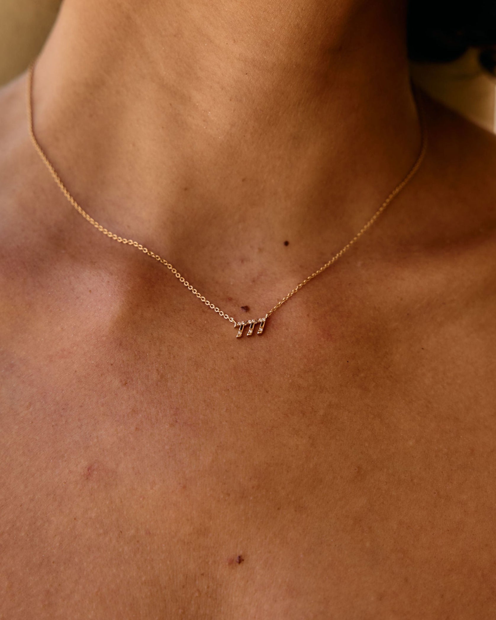 Close-up of a person wearing a delicate gold necklace with small pendants.