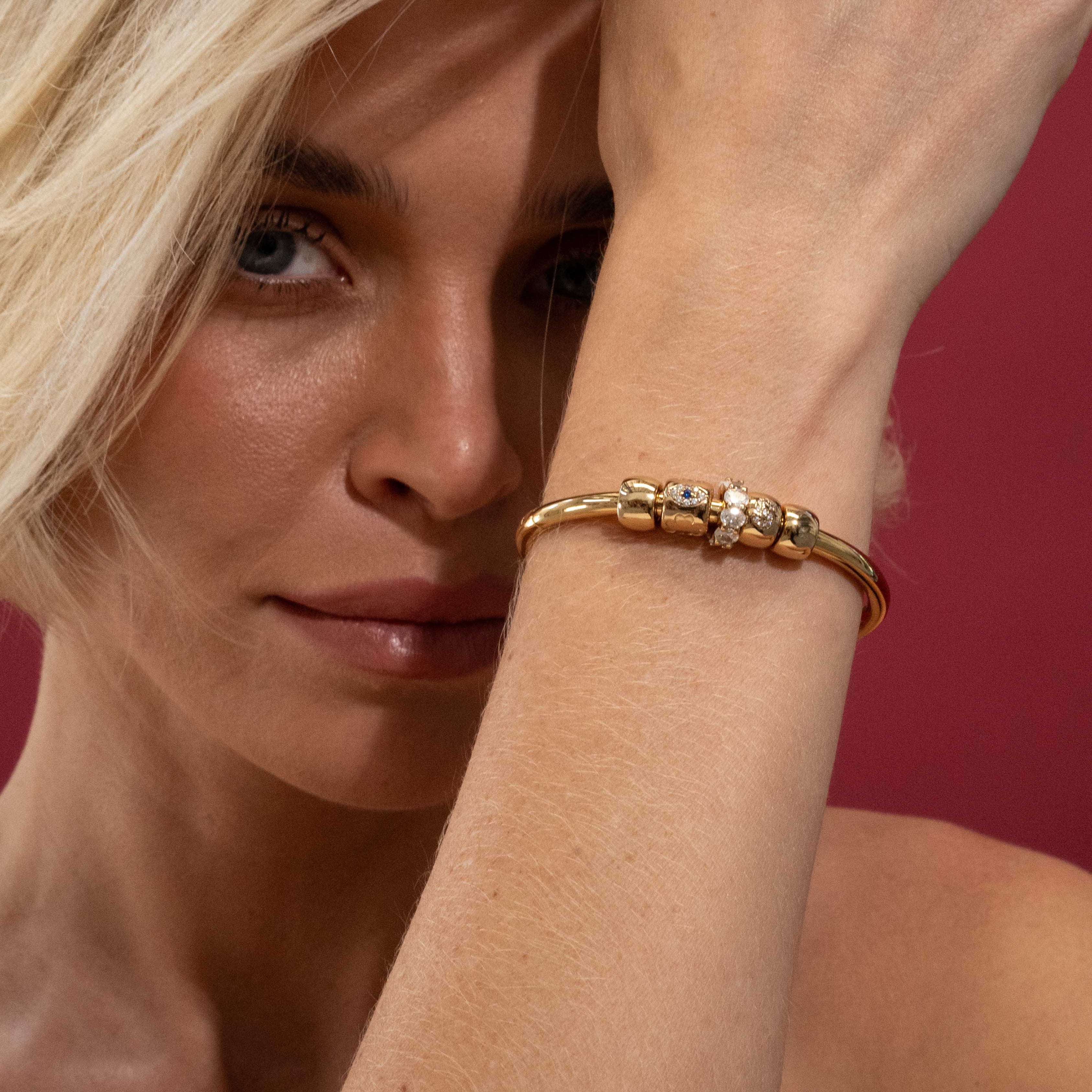 Woman wearing a gold bracelet on a red background