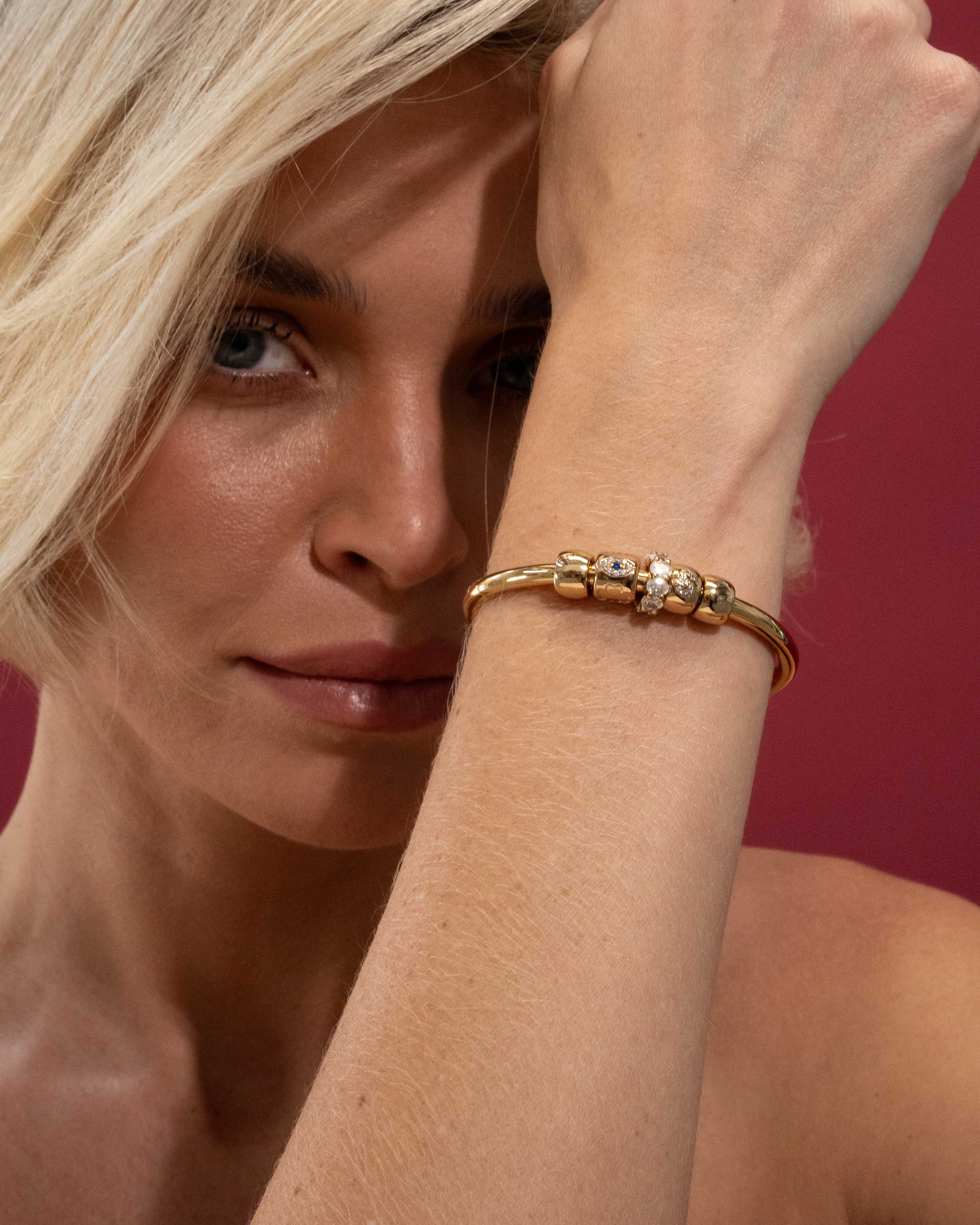 Woman wearing a gold bracelet on a red background