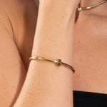 Gold bracelet on a person's wrist with a blurred background
