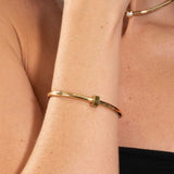 Gold bracelet on a person's wrist with a blurred background