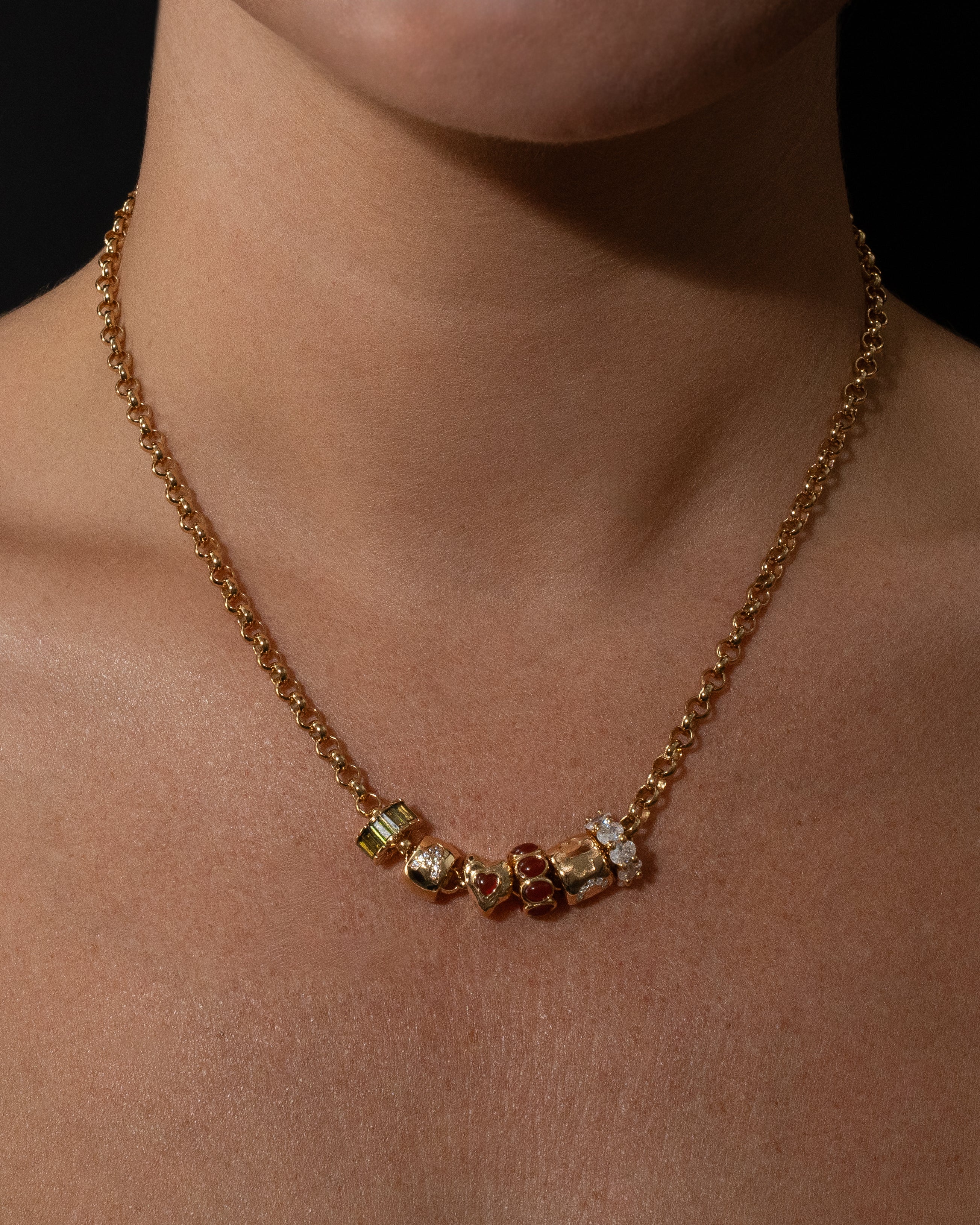 Gold Belcher necklace with beads on a person's neck against a black background