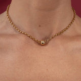 Gold belcher chain necklace on a person's neck with a red background