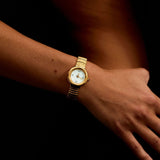 Gold wristwatch on a wrist with a dark background