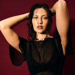 Woman posing with hands behind head against a dark red background