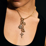 Close-up of a person wearing a gold necklace with charms against a black background