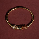 Gold bange with embedded gemstones on a maroon background