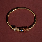 Gold bange with embedded gemstones on a maroon background