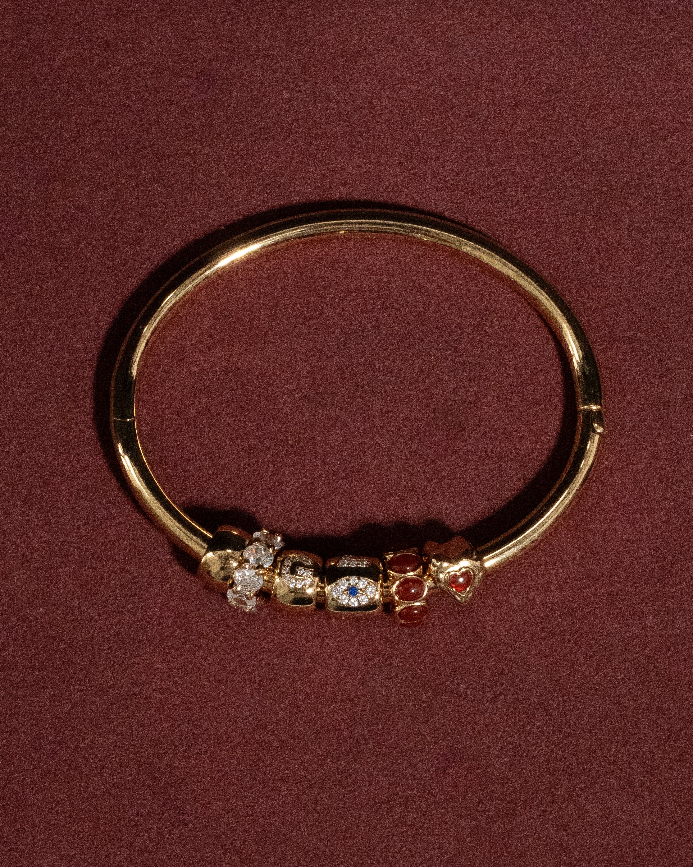 Gold bange with embedded gemstones on a maroon background